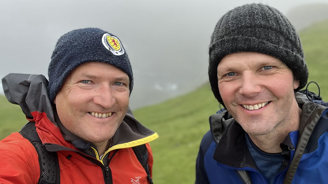 Robin hiking with his neighbour at Hermaness in Shetland with Muckle Flugga in the background